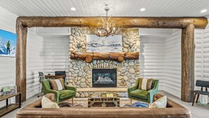 A log cabin interior with a stone fireplace, green upholstered chairs, and a leather sofa. - Abode at Black Bear #330, hot tub, pool table, steps to Deer Valley (Park City)