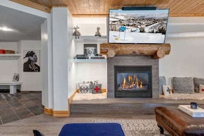 A living room with a fireplace, a television mounted above it, and a cozy seating area.