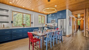 A modern kitchen with wooden ceiling, blue cabinets, and a dining area with red and blue chairs. - Abode at Black Bear #330, hot tub, pool table, steps to Deer Valley (Park City)