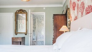 A bedroom with a bed, a wooden dresser, a mirror, a door leading to a bathroom, and a wall with a coral pattern. - NO 108, private room in Aldeburgh (Aldeburgh)