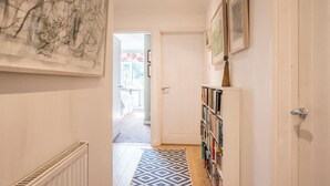 A hallway with a patterned rug, a bookshelf, and a door leading to another room. - NO 108, private room in Aldeburgh (Aldeburgh)
