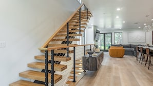 A modern interior with a wooden staircase, a dining area, and a sofa.