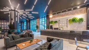 A modern lounge area with sofas, a coffee table, and a bar with a brick wall and plants.