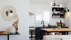 Una cocina moderna con encimera negra, azulejos blancos y una mesa de comedor de madera.