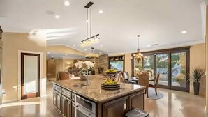 A spacious kitchen with a large island, modern appliances, and a view to the outdoors.