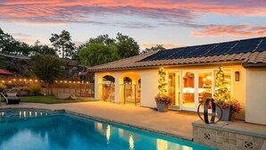 A residential property with a swimming pool, a covered patio, and a solar panel roof.
