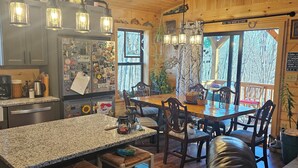 A cozy cabin-style kitchen with a granite countertop, wooden cabinets, and a refrigerator adorned with various magnets.
