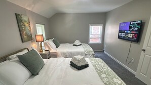 Habitación de hotel con dos camas, un televisor montado en la pared y un cuadro.