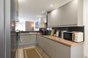Een moderne keuken met een magnetron, fornuis en kastjes.