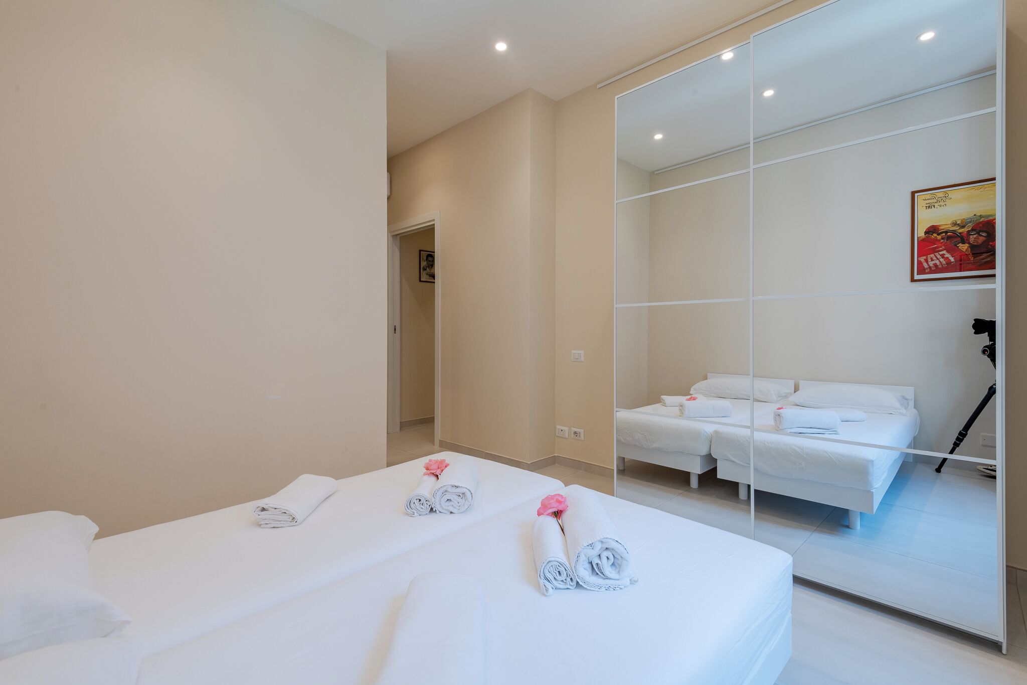 A hotel room with two beds, a large mirror, and a door leading to another room.
