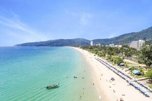 A beach with clear turquoise water, a row of beach umbrellas, and a boat in the water. - 4.11 Karon View 2 Bed, 5 Minutes walk Karon Beach (Karon)
