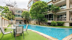Un hotel modern amb piscina, zones d'estar a l'exterior i vegetació abundant.