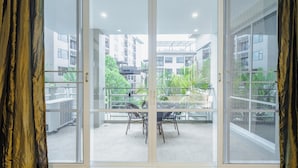 A room with a sliding glass door leading to an outdoor balcony with chairs and a table.