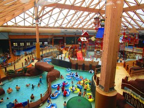 Parque acuático interior con múltiples piscinas, toboganes y estructuras de juego.