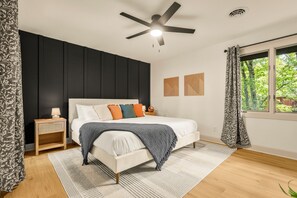 A bedroom with a bed, a nightstand, a ceiling fan, a window with curtains, and a view of greenery outside. - Perfect Summer - Free Pool Access + Prime Location (McGaheysville)