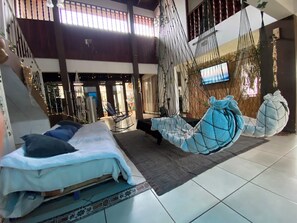 Een ruime kamer met een bed, een hangstoel en een televisie.