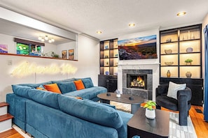 Een moderne woonkamer met een blauwe bank, een open haard en een neonbord.