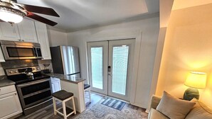 A compact kitchen with modern appliances, a dining area with a small table and chairs, and a cozy seating area with a lamp.