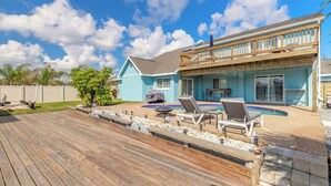 A two-story house with a wooden deck, a swimming pool, and a covered patio area.