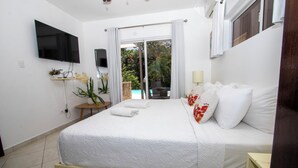 A bedroom with a bed, a TV, a small table with a plant, and a view of a pool through a sliding door. - Luxury Caribbean 5BR Villa – Private Pool, BBQ & Ocean Breezes (Sosúa)