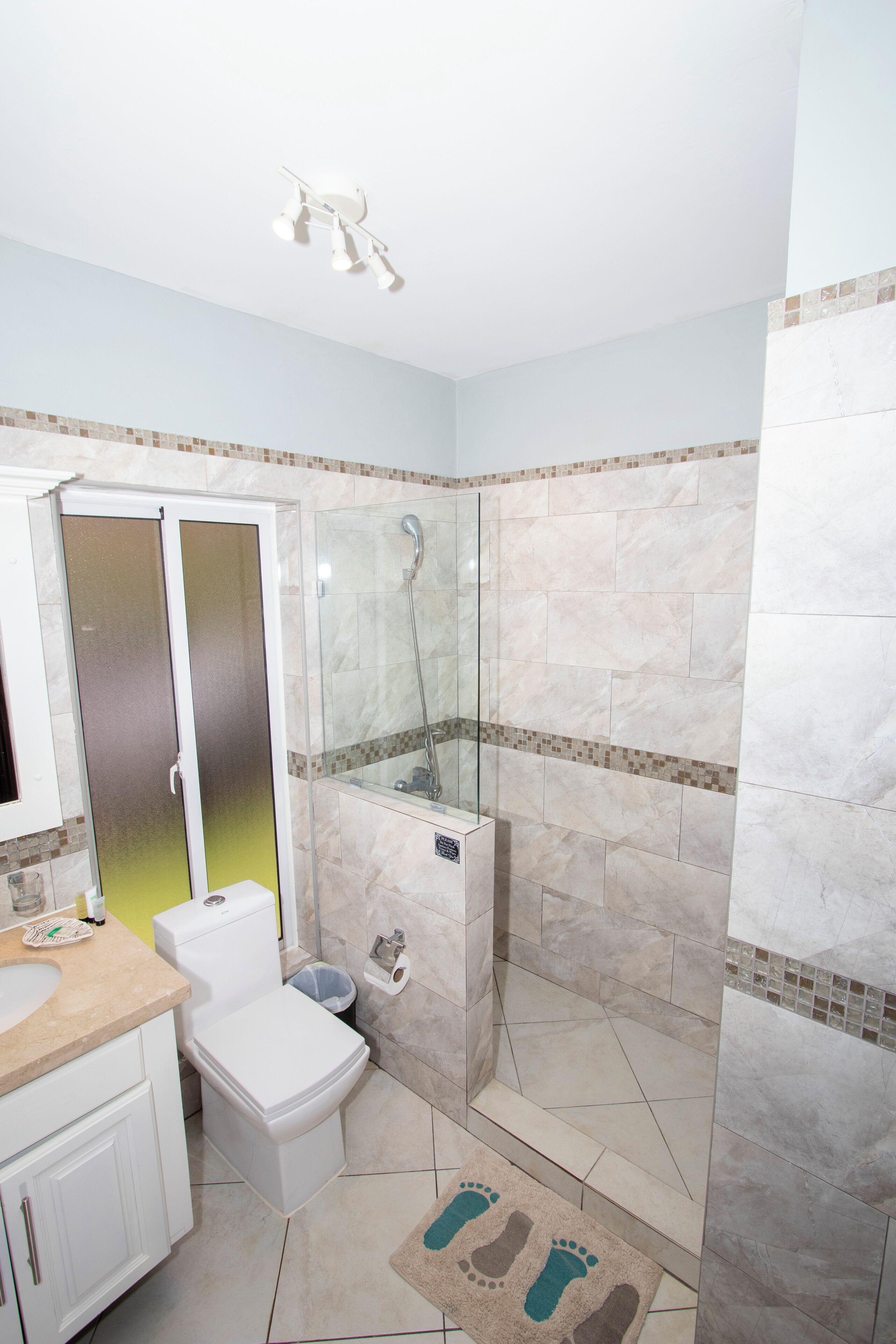 Une salle de bain avec une douche à parois de verre, des toilettes, un lavabo et un miroir.