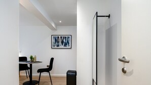 A modern room with a dining area, a black trash bin, and a door with a silver handle. - GuestReady - Prime location near Greenwich Park (London)