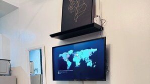 Ett modernt matområde med ett runt bord, två stolar, en världskarta på en väggmonterad TV och ett inramat konstverk ovanför TV:n.
