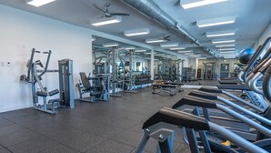 Un gimnasio con cintas de correr, máquinas de pesas y espejos en las paredes.
