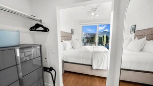 Una habitación de hotel moderna con cama, cómoda, ventana con vista a la montaña y ventilador de techo.