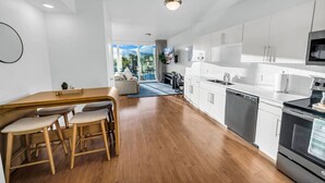 Una cocina moderna con armarios blancos, electrodomésticos de acero inoxidable y una mesa de comedor de madera con sillas.