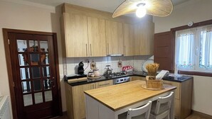 A kitchen with wooden cabinets, a central island with chairs, and a hanging light fixture. - Adorable traditional and functional Farm House. (Guia)