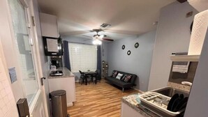 A compact kitchen with a dining area, a ceiling fan, and a small seating area.