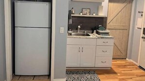 A compact kitchen with a built-in refrigerator, a sink, and a wooden door.