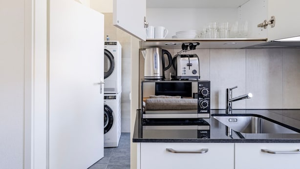 Een compacte keuken met een ingebouwde wasmachine en droger, een broodrooster en een spoelbak.