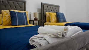 A hotel room with two beds, each with a headboard, and a nightstand with a lamp.