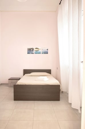 A bedroom with a bed, a nightstand, and a wall-mounted picture. - Double room 1 with private bathroom (Lecce)