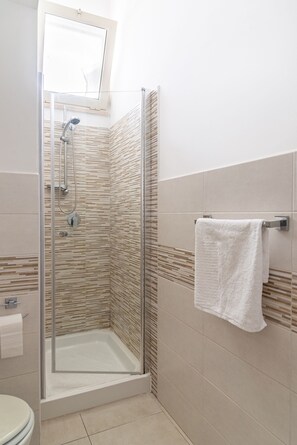 A modern bathroom with a glass-enclosed shower, a toilet, and a towel rack. - Double room 1 with private bathroom (Lecce)
