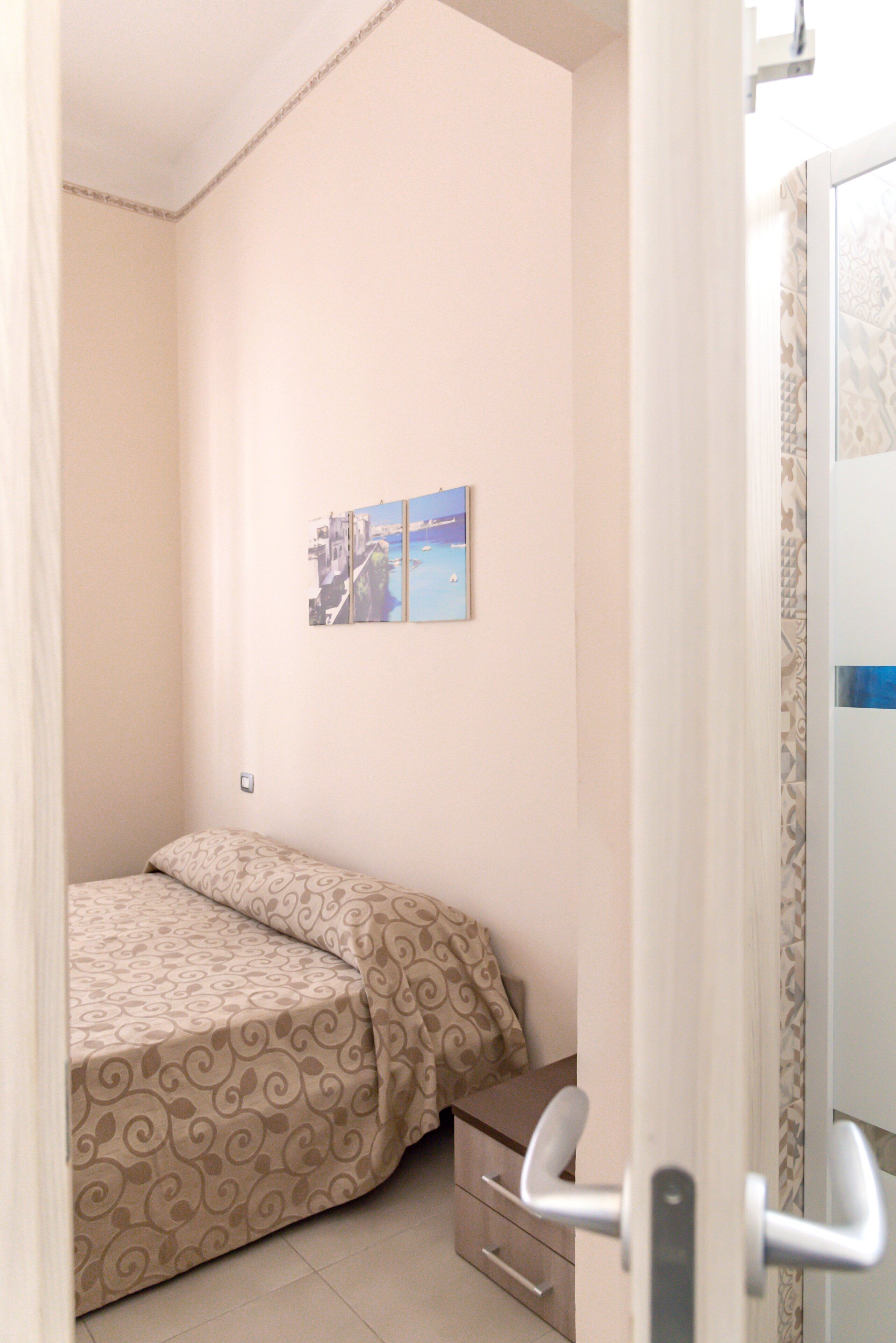 A bedroom with a bed, a small bedside table, and a wall-mounted picture.