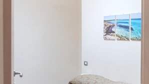 Un dormitorio con una cama, un cuadro en la pared y una puerta.