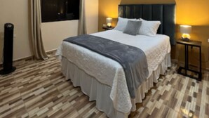 Une chambre moderne avec un grand lit, un luminaire au plafond, une fenĂŞtre avec des rideaux et une table de chevet avec une lampe.