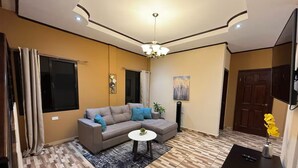 Un salon avec un canapé, une table basse, un téléviseur et une porte.