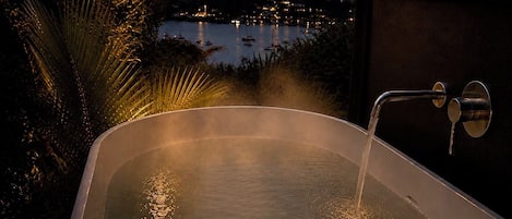 A hot tub with a view of a body of water and a night sky.