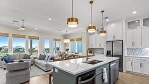 A modern kitchen with a central island, stainless steel appliances, and white cabinetry. - Terramar Beach Escape + Easy Beach Access (Galveston)