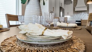 A dining table set with white napkins, clear glassware, and woven placemats. - Terramar Beach Escape + Easy Beach Access (Galveston)