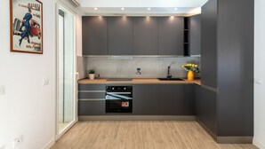 Une cuisine moderne avec des meubles de couleur sombre, un four encastré et un plan de travail en bois.