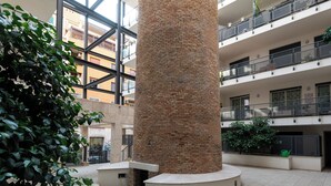 Un vaste atrium doté d’une colonne centrale en briques, entouré de balcons et de verdure.