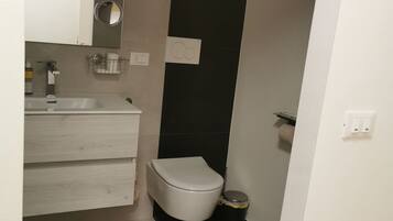Ein modernes Badezimmer mit Toilette, Waschbecken und Spiegel.