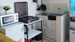Una cucina compatta con piano cottura a gas, microonde e un piccolo frigorifero.