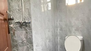 Un bagno con doccia, servizi igienici e una finestra.