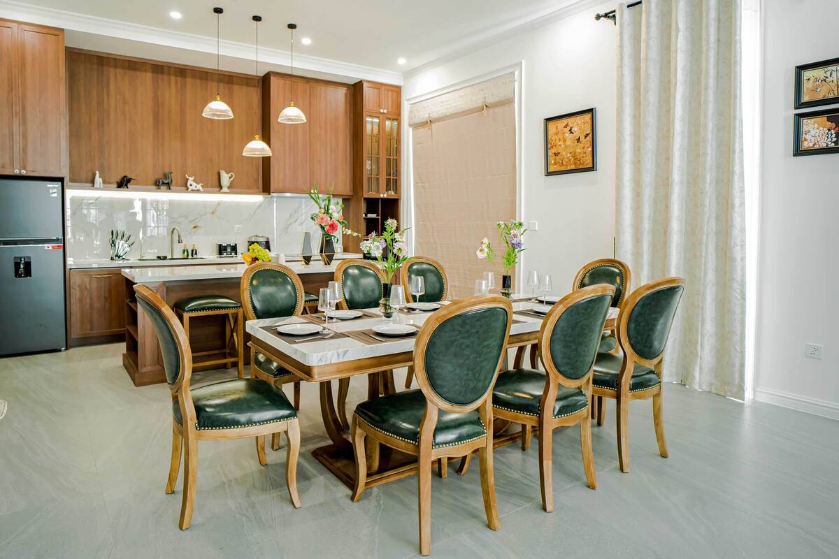 A modern kitchen with wooden cabinets, a built-in refrigerator, and pendant lighting.